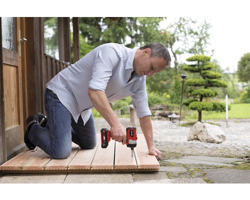 Man monteert houten tegels met een accuschroevendraaier buitenshuis