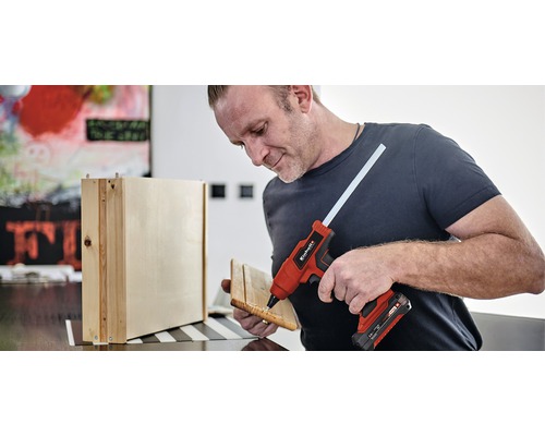 Man gebruikt een lijmpistool om houten onderdelen aan elkaar te lijmen.