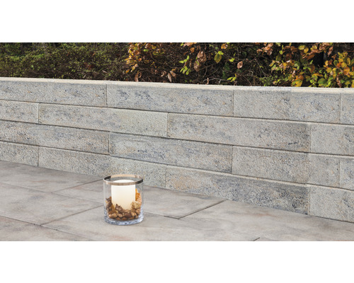 Tuinmuur van steen met decoratieve kaars in glas