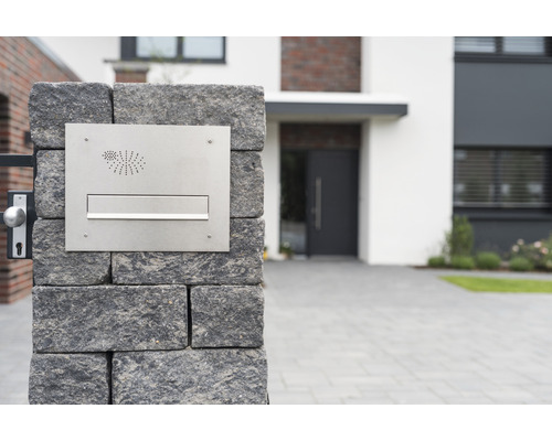 Roestvrijstalen brievenbus op een stenen muur voor een woonhuis