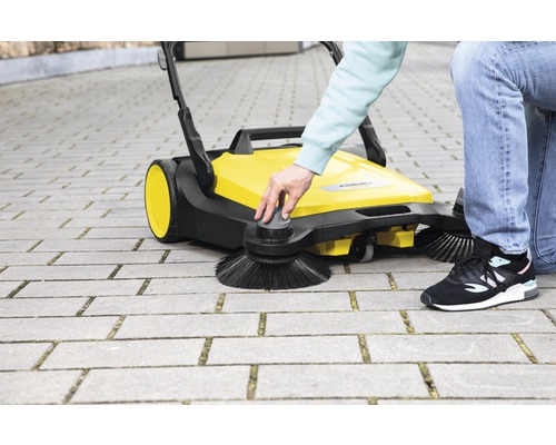 Gele Kärcher veegmachine in gebruik op straatstenen