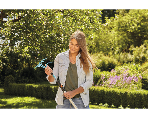 Vrouw houdt een tuinklauwopzetstuk met steel vast in een tuin