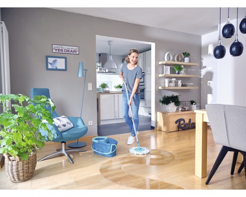 Vrouw dweilt houten vloer in lichte woonkamer met dweil