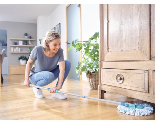 Vrouw dweilt houten vloer in de woonkamer met een dweil