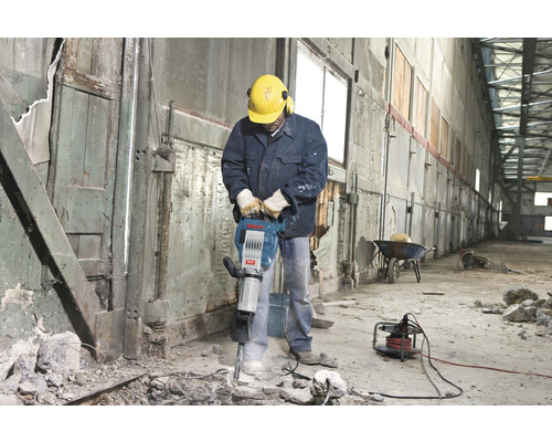 Bouwvakker met drilboor die sloopwerkzaamheden verricht in een gebouw.
