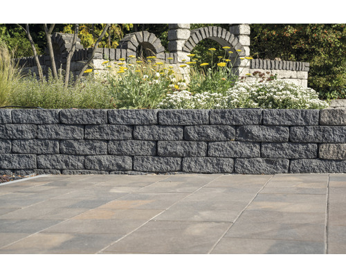 Tuinmuur van stenen met planten en stenen bogen op de achtergrond