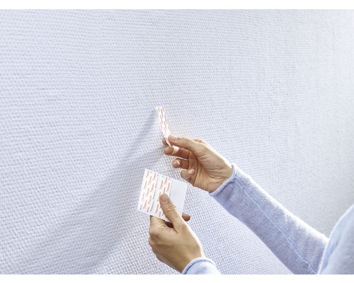 Persoon bevestigt kleefstrips aan een muur