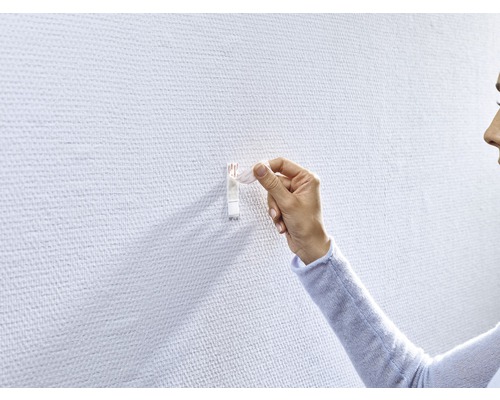 Vrouw bevestigt een zelfklevende haak aan een muur