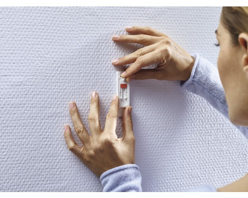 Vrouw bevestigt een zelfklevende haak aan de muur