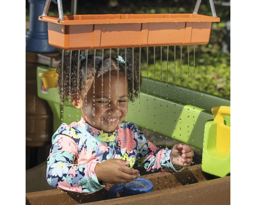 Meisje speelt met waterspeeltafel in de tuin