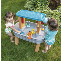Twee kinderen spelen met een Step2 waterspeeltafel in de tuin.