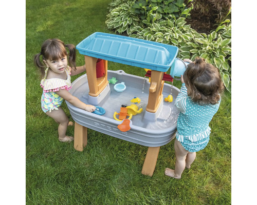 Twee kinderen spelen met een Step2 waterspeeltafel in de tuin.