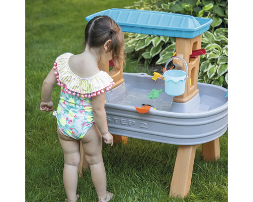 Meisje speelt met Step2 waterspeeltafel in de tuin
