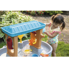 Klein meisje speelt met een water- en zandtafel in de tuin