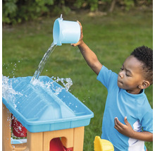 Kind giet water op een speeltafel buitenshuis.