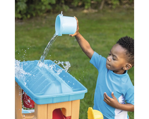 Kind giet water op een speeltafel buitenshuis.