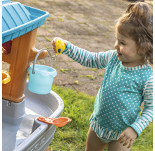 Een jong kind speelt met een waterspeeltafel buiten.