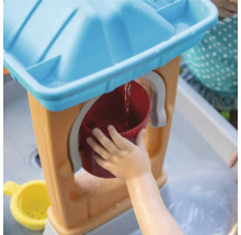 Kind speelt met een waterspeeltafel en een emmer.