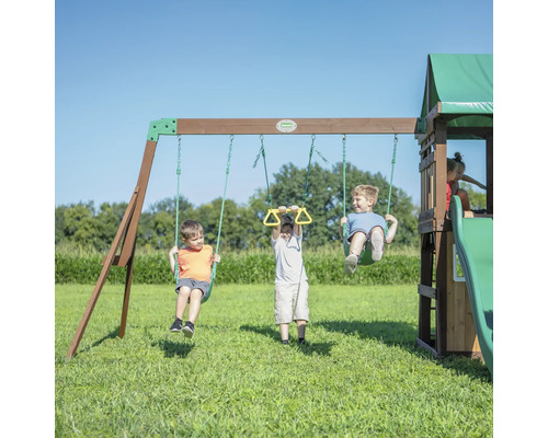 Kinderen spelen op een speelplaats met schommels, gymnastiekringen, glijbaan en speelhuis.