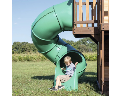Jongen op een groene tunnelglijbaan in een speeltuin