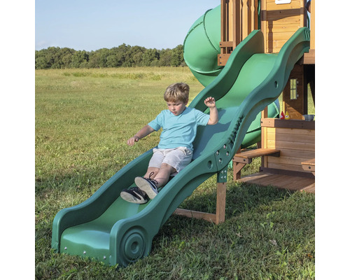 Jonge glijdt van een groene kinderglijbaan.