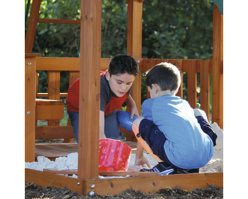 Twee kinderen spelen in de zandbak van een speeltoestel.
