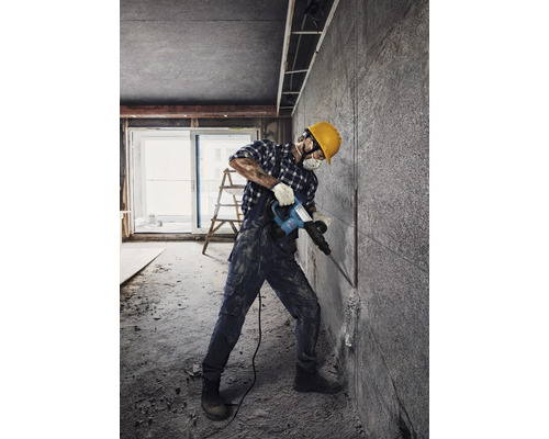 Ambachtsman met een sloophamer tijdens renovatiewerkzaamheden in een ruimte.