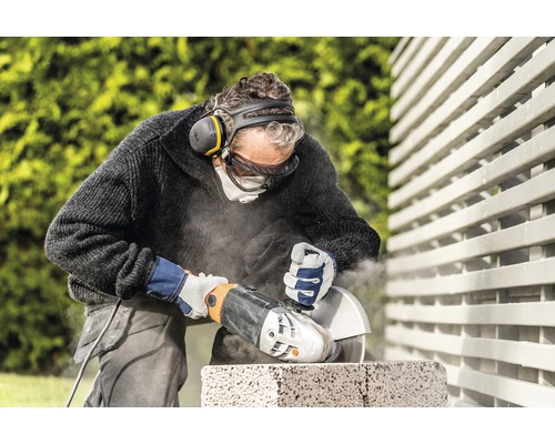 Ambachtsman snijdt steen met een haakse slijper, terwijl hij beschermende kleding draagt
