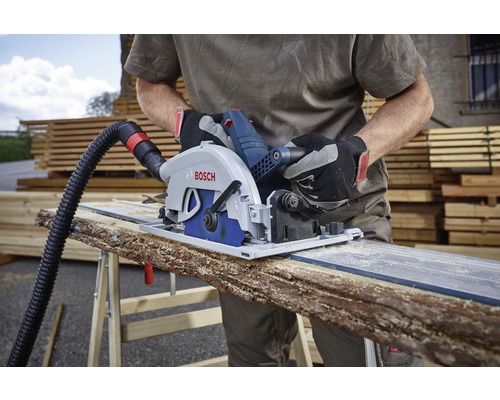 Een persoon gebruikt een invalcirkelzaag met stofafzuiging om een houten plank te zagen. Bosch Logo zichtbaar.