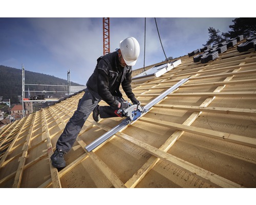 Een vakman zaagt met een handcirkelzaag een houten dak op maat.
