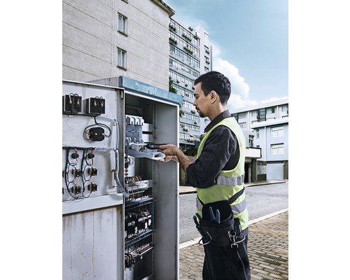 Elektricien werkt aan een open schakelkast buiten.