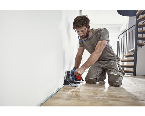 Man snijdt houten vloer met een invalzaag.