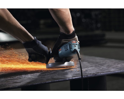 Een man bewerkt een stuk metaal met een haakse slijper, waarbij vonken ontstaan.