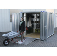 Stalen container met helling en rekken. Een vrouw duwt een kruiwagen met buizen in de container.
