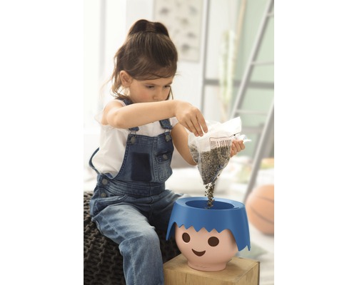 Een meisje giet zaden in een plantenpot met een gezicht