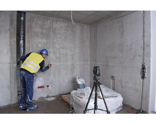 Bouwvakker markeert muur met laserwaterpas in een casco gebouw