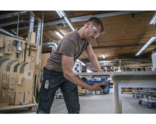 Man zaagt hout met decoupeerzaag in werkplaats