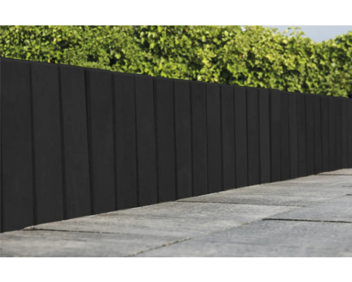 Donkere houten privacyscherm naast een verhard pad