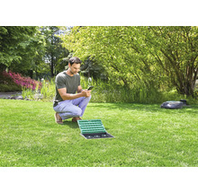 Man bedient tuinbewateringssysteem met smartphone in de tuin.