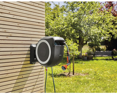 Tuinslangbox met slang en sproeier voor tuinbesproeiing gemonteerd op een houten wand