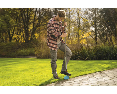 Een man gebruikt een graskantsteker in de tuin om graskanten te bewerken