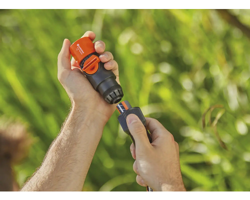 Iemand verbindt een Gardena waterstopconnector met een tuinslang.