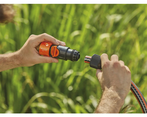 Een persoon verbindt een Gardena slangstuk met een kraanaansluiting.