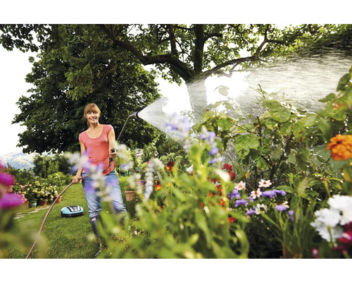 Vrouw besproeit planten in de tuin met een tuinslang