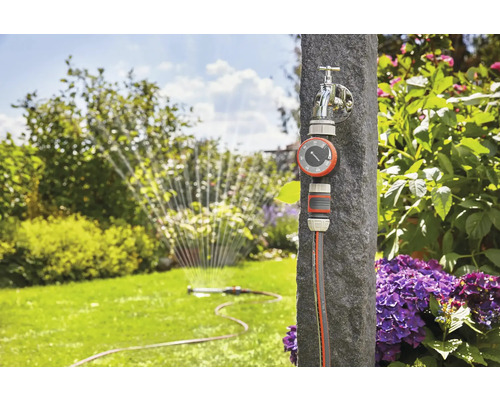 Tuinbewateringssysteem met waterkraan, bewateringsklok en tuinslang in de tuin