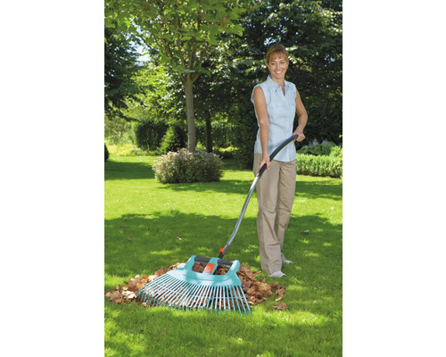 Vrouw harkt bladeren met een tuinhark in de tuin.