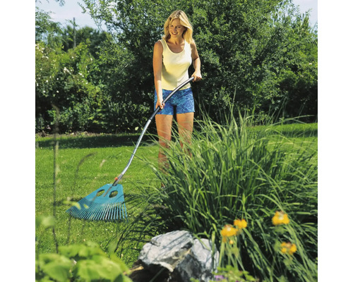 Een vrouw gebruikt een bladhark in de tuin om bladeren en tuinafval te verwijderen.