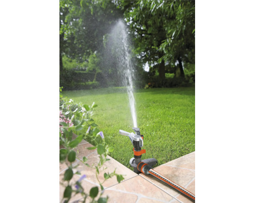 Tuinscène met gazonsproeier die het gazon besproeit
