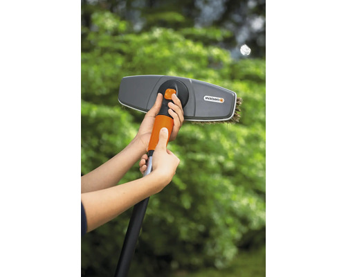 Persoon monteert een Gardena wasborstel op een telescopische stang voor tuinwerkzaamheden.