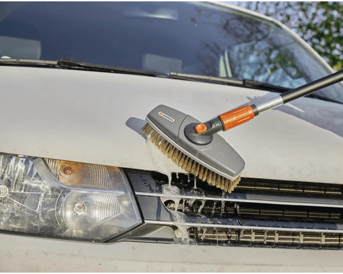 Een autowasborstel met telescoopsteel reinigt een auto.
